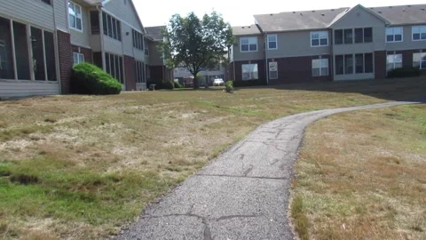 POV forward tracking shot on curved sidewalk w/ pond and apartment buildings Stock Footage 201500559
