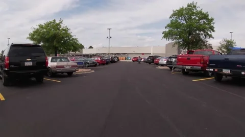 POV FPV driving through a Walmart parking lot with people and parked cars Stock Footage 153563729
