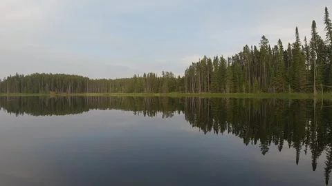 POV from the front of a canoe moving slowly on a calm river reflecting a Stock Footage 326969691