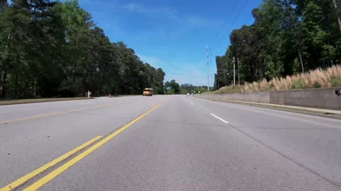 POV ground view passing a yellow school bus  on a highway Stock Footage 196640391