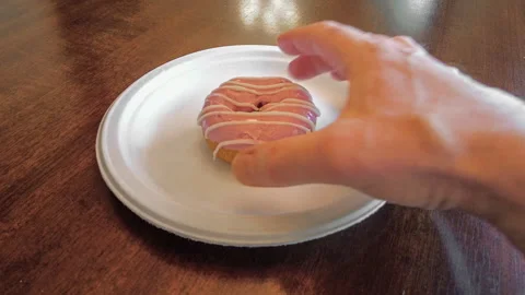 POV of Hand Reaching for Glazed Donut With a Bite Taken Out on Paper Plate 스톡 동영상 336816262