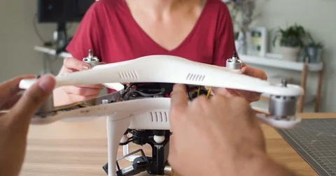 POV of hands assembling a robot drone with an attractive young female tech Vídeo Stock 84292462