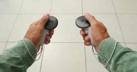 POV of hands holding white controllers, plays in virtual reality. Stock Footage 257584418