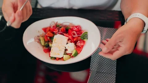 POV of hands using a fork to eat fresh greek salad with feta cheese outdoors. Vídeos de archivo 340845110