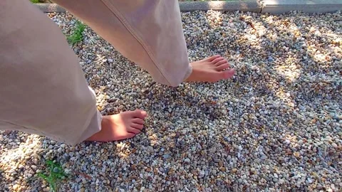 POV High Angle Shot of Bare Feet Walking on Gravel Sensory Path in Slow Motion Stock Footage 345618462