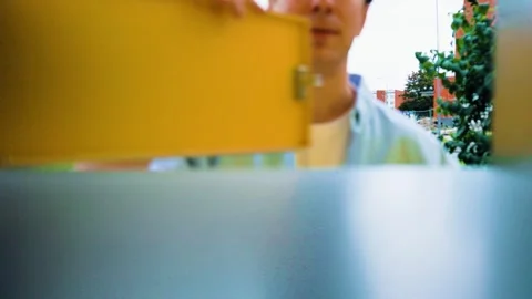 POV inside a parcel locker: a man opens the yellow door to drop off a package. C Stock Footage 342341613