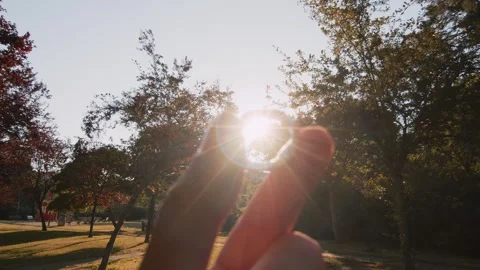 POV looking at an engagement ring against the backdrop of a sunset in a park in Stock Footage 245907450