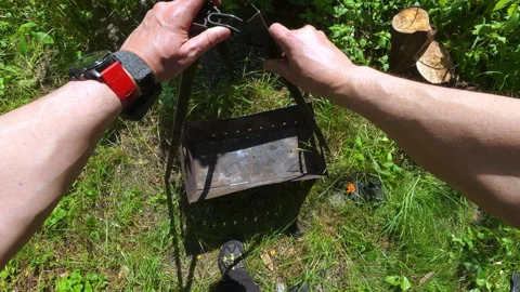 POV man assembling metal tripod over portable grill for outdoor picnic prep.. Video stock 343550701
