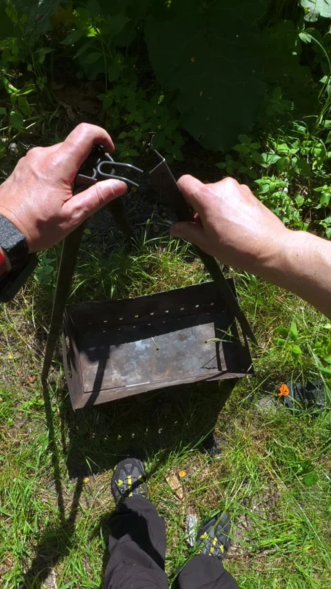 POV man assembling metal tripod over portable grill for outdoor picnic prep.. Video stock 346718528