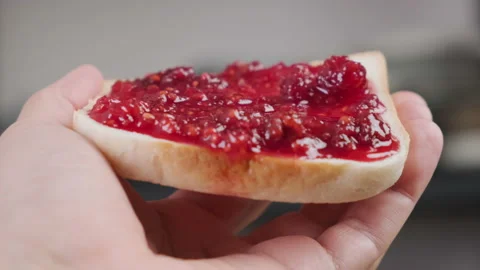 POV man eats bread toast spread with raspberry jam Stock Footage 218460957