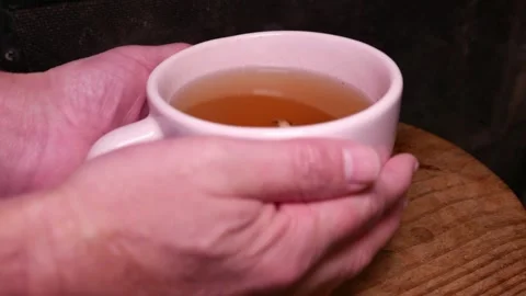 POV: man holding and moving a teacup by the fireplace. A cup of ginger tea. Stock Footage 336433672