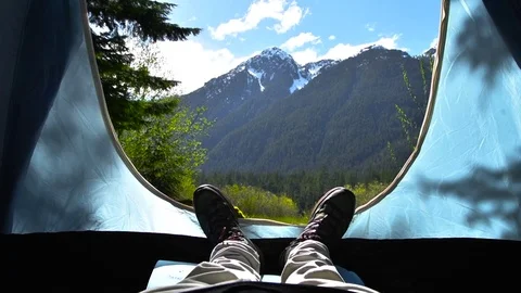 POV of man laying in tent looking out at nature through tent flaps Stockbeeldmateriaal 83874553