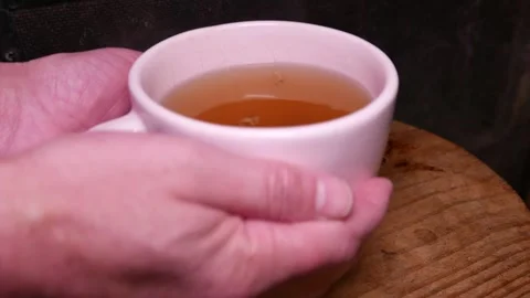 POV: A man picking up a teacup from a table. Ginger tea with honey. A fireplace Stock Footage 335426994