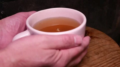 POV: man placing a cup of ginger tea on a table. A mug of ginger tea with honey. Stock Footage 335966220