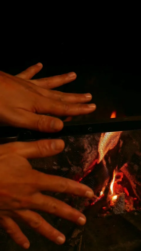 POV: man warming up his hands by the fireplace. Firewood burning in a fireplace Stock Footage 335053181
