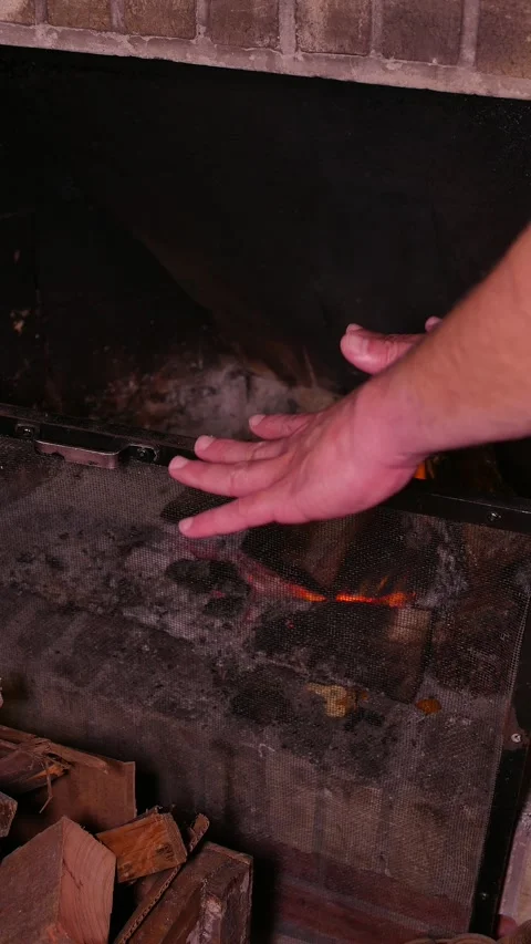 POV: man warming up his hands by the fireplace. Firewood burning. Firewood box Stock Footage 336151923
