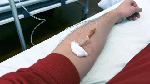 POV of a man's arm with an IV needle in the median cubital vein in a clinic ward Stock Footage 260577798