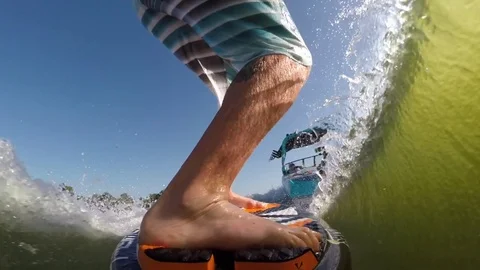 POV of a man’s legs while wake surfing behind a boat on a lake. Stock Footage