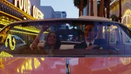 Pov Ms Couple Driving Through Neon Illuminated City Street In Convertible Car At Stock Footage