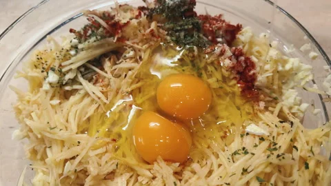 POV opening egg to add into grated potato. Cooking hash browns at home Stock-Footage 260265170