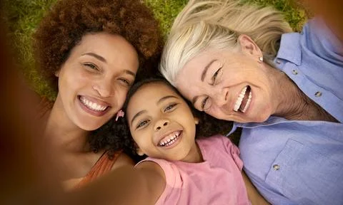 POV Overhead Shot Of Multi-Generation Female Family Lying On Grass Taking Selfie Stock Photos