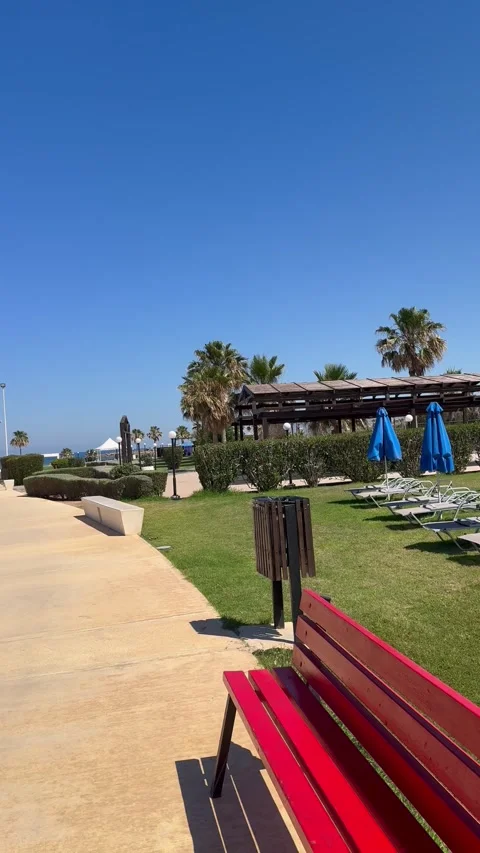 POV panoramic moving shot past beach sunbeds and blue umbrellas towards resort Stock Footage 336219121