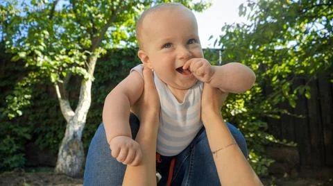 POV of parent holding and lifting up cute baby son in garden. Parenting, family Foto stock