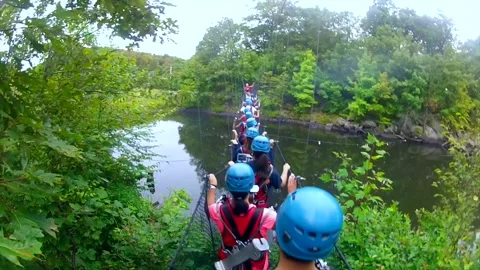 POV - People playfully jumps while crossing cable supported pedestrian bridge Stock Footage 136975047