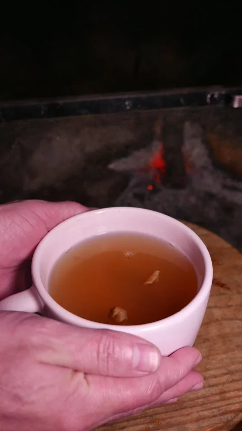 POV: placing a cup of ginger and honey tea on a table in front of a fireplace Stock Footage 335177197