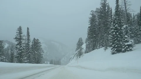 POV Scenic view of driving down the snowy asphalt road leading toward Teton Pass Stock Footage 123071859