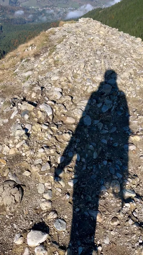 POV shadow walking to edge then panning up to autumn lake and Ceahlau mountains Stock Footage 344412628