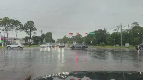 A POV shot from inside a car of an intersection during a rain storm Vídeo Stock 342600316