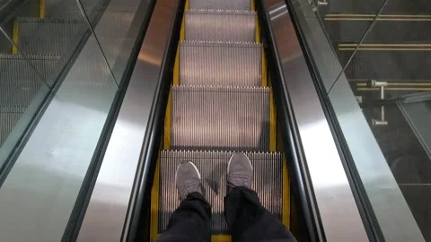 POV shot of a man standing on an escalator, looking down at his feet. Stock Footage 318267474
