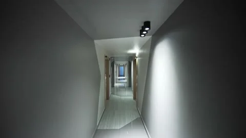 POV shot slowly walking down a modern hotel hallway. Corridor with many doors. Видео 201193701