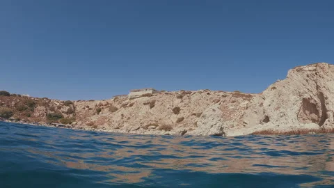 POV shot, split level, guy paddling with his hands underwater to rocky shore Video stock 254423592
