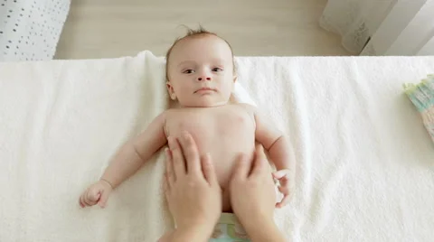 POV shot of young mother massaging 3 months old baby lying on changing table Stock Footage