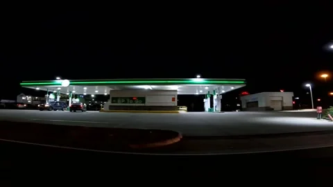 POV side pan BP gas station people and cars at night 3.83 a gallon Stock Footage 177671838