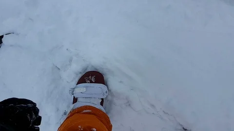 POV of snowboarder correcting his binding, while the snowboard is covered in pow Stock Footage 86324000