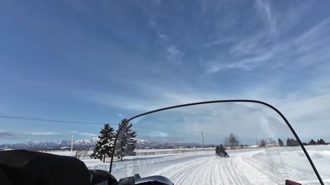 POV snowmobile ride under dramatic blue sky over snowy field Hokkaido Stock Footage 333230146