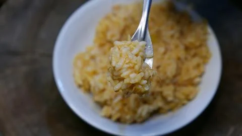 POV: Someone eating risotto with a fork. A plate of risotto on the table. Fotos de archivo