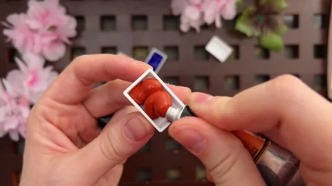 POV squeezing out brown paint from metal tube into plastic pan. Basic colors in 库存影片 262314422