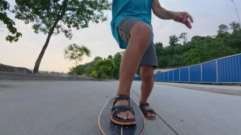 POV-style low angle shot of child riding skateboard on street, close up of feet Stock Footage 316222986