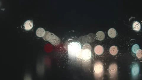 POV through rainy car windshield with blurred traffic lights at night Stock Footage 344483778