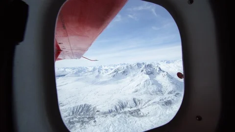 POV of Tordrillo mountains viewed through airplane window, red wing in the shot Stock Footage 129129657