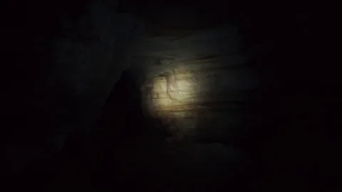 POV tracking shot following through light flare on wall in cave. Stock Footage