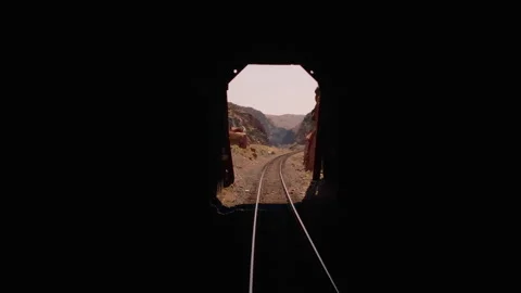 POV train in mountain valley tracks near river through tunnel Stock Footage 247560509