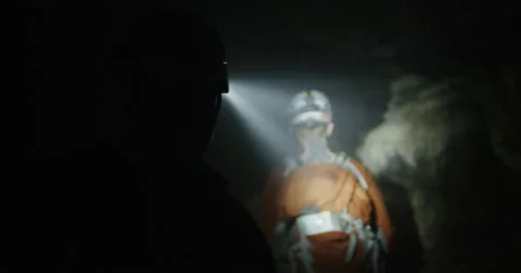 POV two explorers walking through a cave in slow motion with headlamps smoke Stock Footage 64682933