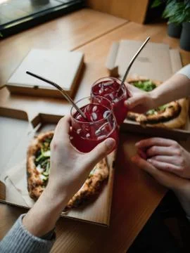 Pov, two pizzas in boxes on a table with lemonade in hands, clink glasses Stock Photos