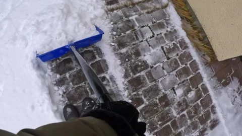 POV two-stage winter clearing: scraping hard-packed ice then sweeping powder Stock Footage 328063471