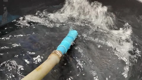 POV using a water hose and pipe to fill up a black plastic tank. Stock Footage 280847746